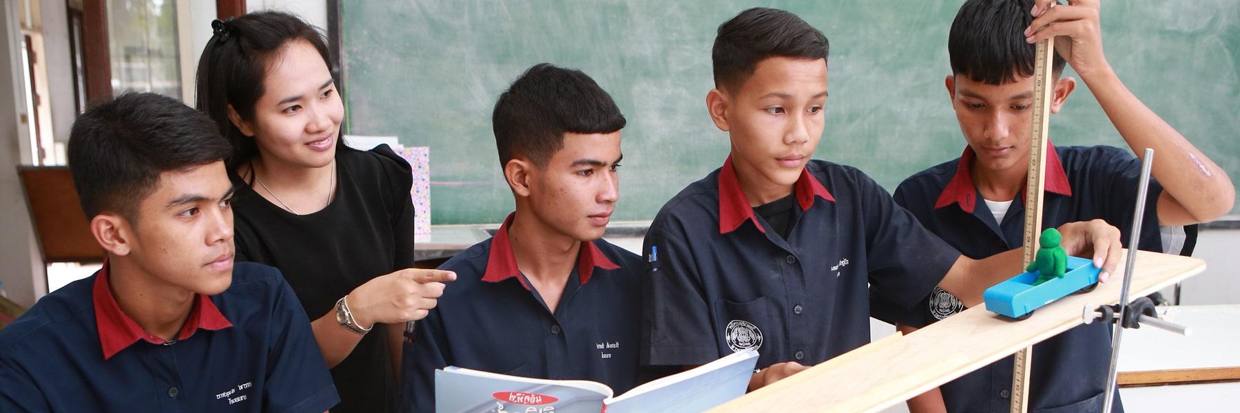 students stand horizontally at a table while conducting an experiment