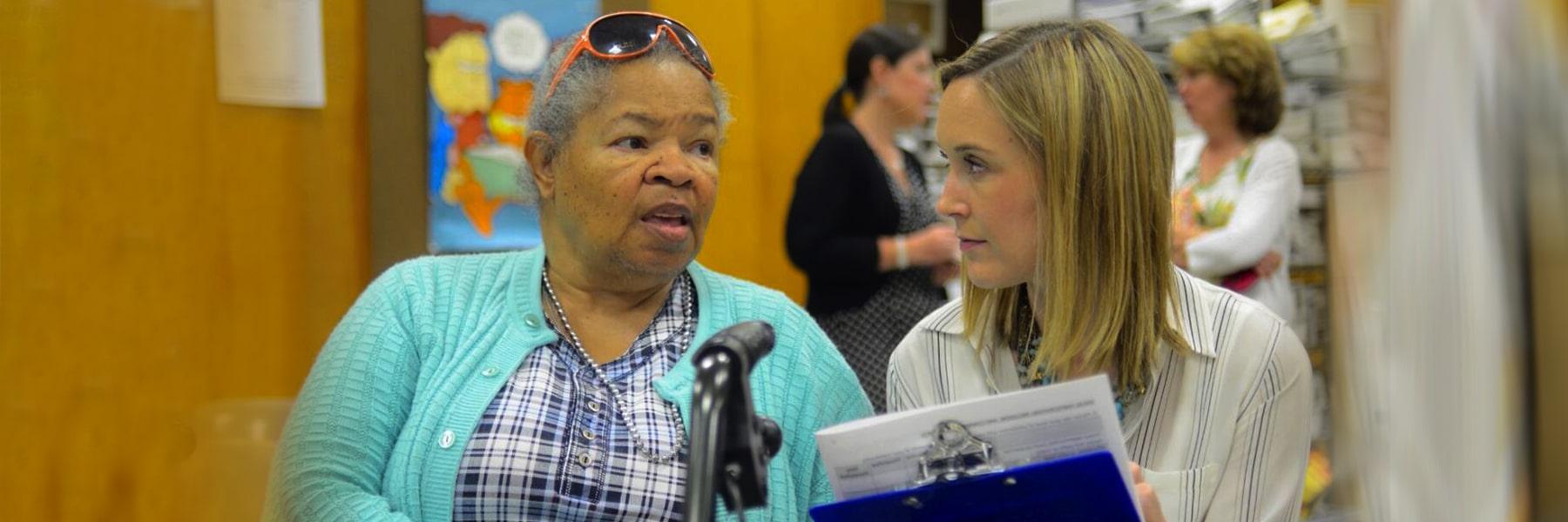 Two women talk at microphone at community engaged event.